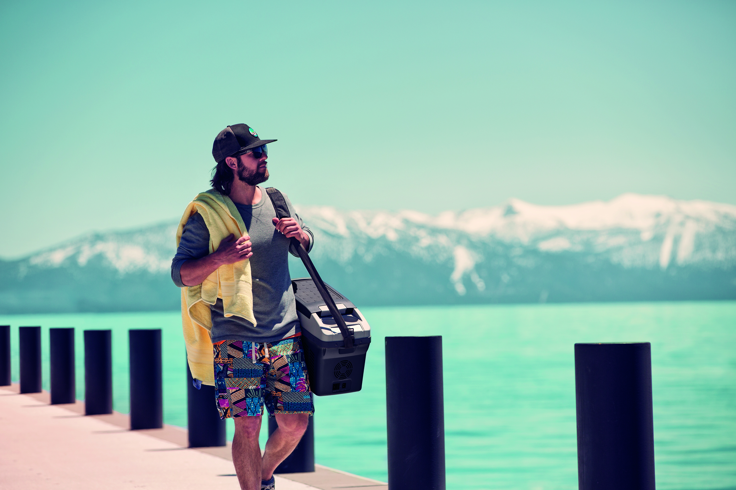 Voyageur avec sa glacière au bord d'un lac de montagne